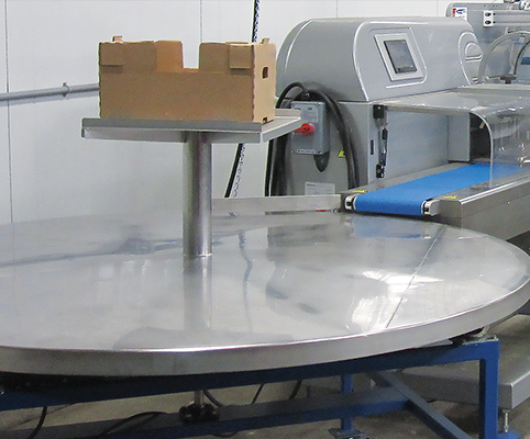 Una mesa de recolección giratoria se encuentra al final de una máquina de envoltura de flujo para organizar los productos