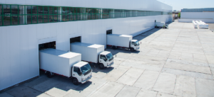 Varios camiones blanco de entrega se cargan en una instalación de almacén