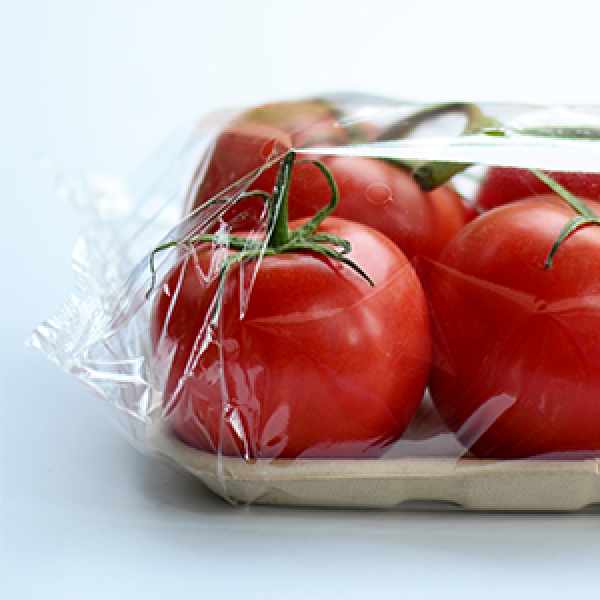 Varios tomates de color rojo brillante asentados en una bandeja de fibra envuelta en envases de envoltura de flujo